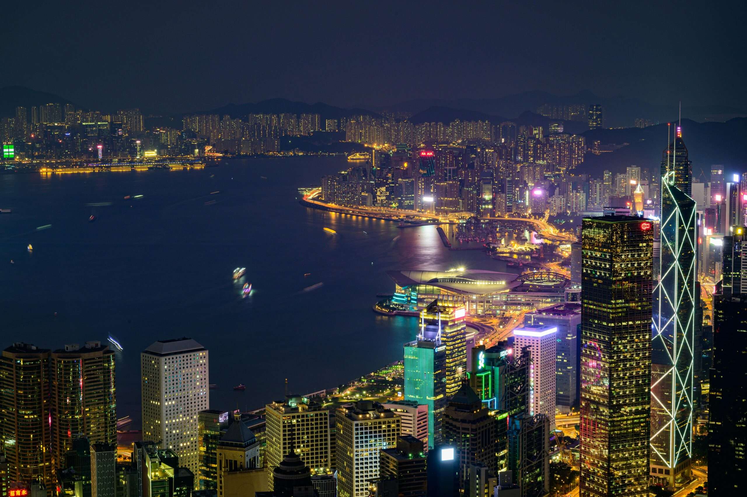 Stunning nighttime view of Hong Kong Island with illuminated skyscrapers and vibrant cityscape across Victoria Harbor.